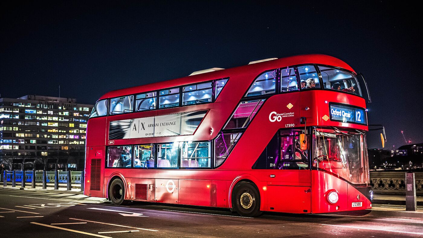 A red New Routemaster bus on route 12 in London at night